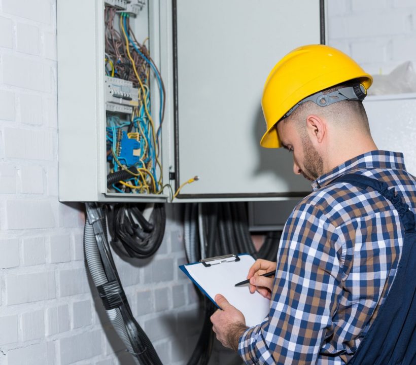 Professional electrician inspecting wires in electrical box